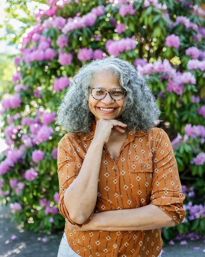 Karen Trice, LMFT-A, smiling in front of blooming rhododendrons